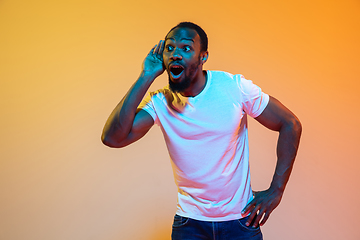 Image showing African-american man\'s portrait isolated on gradient orange studio background in neon light