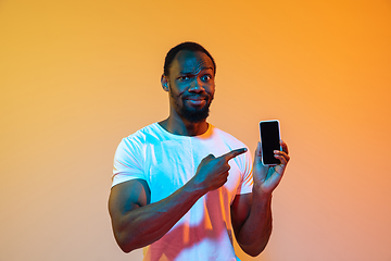 Image showing African-american man\'s portrait isolated on gradient orange studio background in neon light