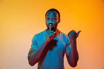 Image showing African-american man\'s portrait isolated on gradient orange studio background in neon light