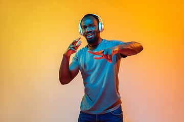 Image showing African-american man\'s portrait isolated on gradient orange studio background in neon light