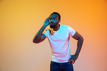 Image showing African-american man\'s portrait isolated on gradient orange studio background in neon light