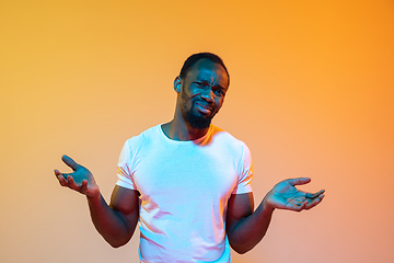 Image showing African-american man\'s portrait isolated on gradient orange studio background in neon light