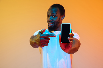 Image showing African-american man\'s portrait isolated on gradient orange studio background in neon light