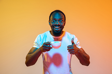 Image showing African-american man\'s portrait isolated on gradient orange studio background in neon light