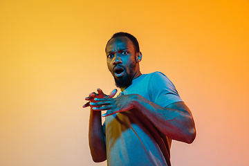 Image showing African-american man\'s portrait isolated on gradient orange studio background in neon light