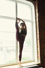 Image showing Sporty young woman practicing yoga at home