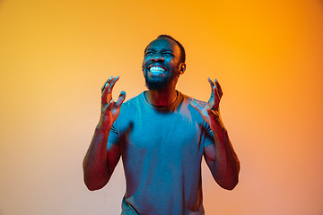 Image showing African-american man\'s portrait isolated on gradient orange studio background in neon light