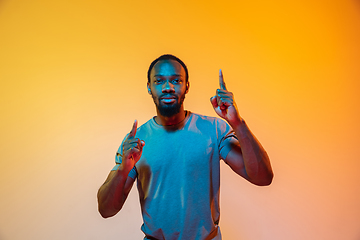 Image showing African-american man\'s portrait isolated on gradient orange studio background in neon light