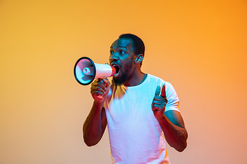 Image showing African-american man\'s portrait isolated on gradient orange studio background in neon light