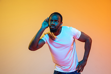 Image showing African-american man\'s portrait isolated on gradient orange studio background in neon light