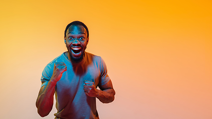 Image showing African-american man\'s portrait isolated on gradient orange studio background in neon light