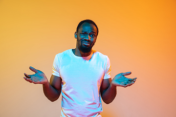 Image showing African-american man\'s portrait isolated on gradient orange studio background in neon light