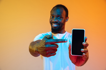 Image showing African-american man\'s portrait isolated on gradient orange studio background in neon light