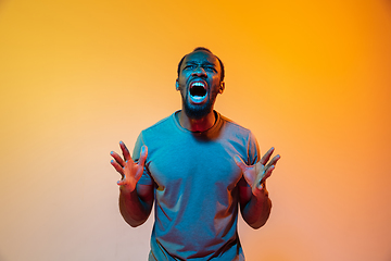 Image showing African-american man\'s portrait isolated on gradient orange studio background in neon light