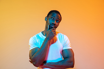 Image showing African-american man\'s portrait isolated on gradient orange studio background in neon light