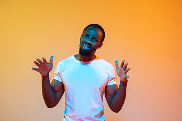 Image showing African-american man\'s portrait isolated on gradient orange studio background in neon light