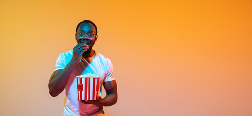 Image showing African-american man\'s portrait isolated on gradient orange studio background in neon light