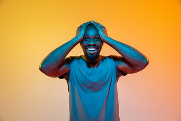 Image showing African-american man\'s portrait isolated on gradient orange studio background in neon light