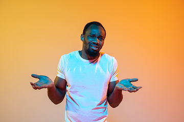 Image showing African-american man\'s portrait isolated on gradient orange studio background in neon light