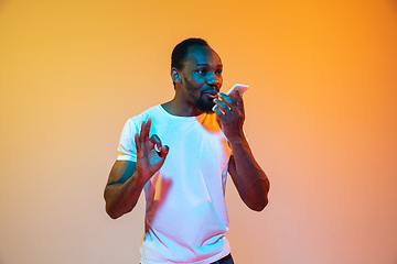 Image showing African-american man\'s portrait isolated on gradient orange studio background in neon light