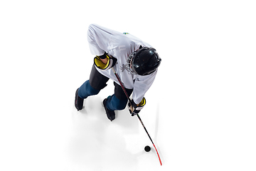 Image showing Unrecognizable male hockey player with the stick on ice court and white background