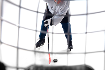 Image showing Unrecognizable male hockey player with the stick on ice court and white background