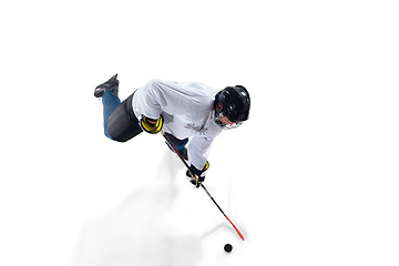 Image showing Unrecognizable male hockey player with the stick on ice court and white background