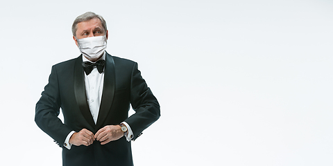 Image showing Elegance senior man waiter in protective face mask on white background. Flyer with copyspace.