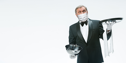 Image showing Elegance senior man waiter in protective face mask on white background. Flyer with copyspace.