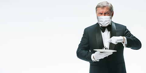 Image showing Elegance senior man waiter in protective face mask on white background. Flyer with copyspace.