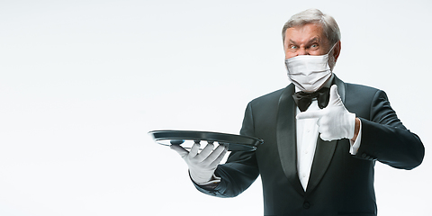 Image showing Elegance senior man waiter in protective face mask on white background. Flyer with copyspace.