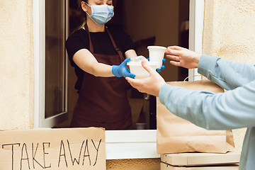 Image showing Woman preparing drinks and meals, wearing protective face mask and gloves. Contactless delivery service during quarantine coronavirus pandemic. Take away only concept.