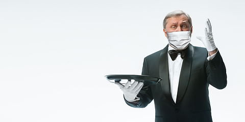 Image showing Elegance senior man waiter in protective face mask on white background. Flyer with copyspace.