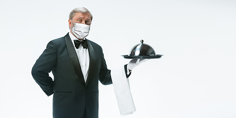 Image showing Elegance senior man waiter in protective face mask on white background. Flyer with copyspace.