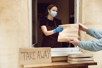 Image showing Woman preparing drinks and meals, wearing protective face mask and gloves. Contactless delivery service during quarantine coronavirus pandemic. Take away only concept.