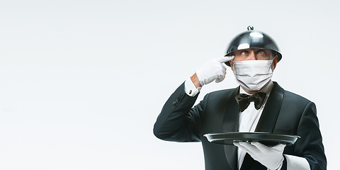 Image showing Elegance senior man waiter in protective face mask on white background. Flyer with copyspace.