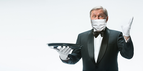 Image showing Elegance senior man waiter in protective face mask on white background. Flyer with copyspace.