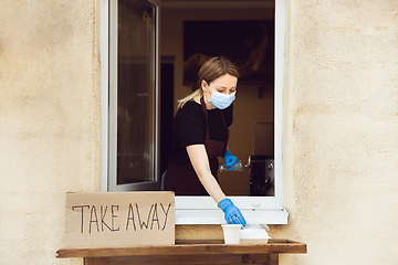 Image showing Woman preparing drinks and meals, wearing protective face mask and gloves. Contactless delivery service during quarantine coronavirus pandemic. Take away only concept.