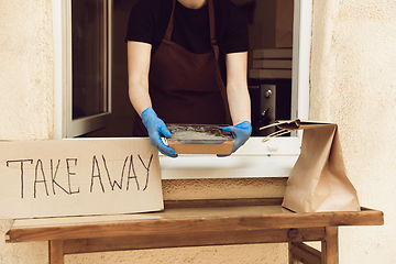 Image showing Woman preparing drinks and meals, wearing protective face mask and gloves. Contactless delivery service during quarantine coronavirus pandemic. Take away only concept.