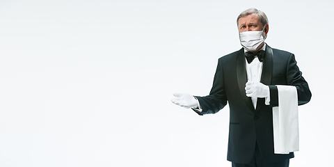 Image showing Elegance senior man waiter in protective face mask on white background. Flyer with copyspace.