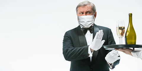 Image showing Elegance senior man waiter in protective face mask on white background. Flyer with copyspace.