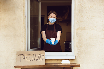 Image showing Woman preparing drinks and meals, wearing protective face mask and gloves. Contactless delivery service during quarantine coronavirus pandemic. Take away only concept.