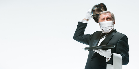 Image showing Elegance senior man waiter in protective face mask on white background. Flyer with copyspace.