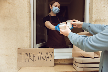 Image showing Woman preparing drinks and meals, wearing protective face mask and gloves. Contactless delivery service during quarantine coronavirus pandemic. Take away only concept.