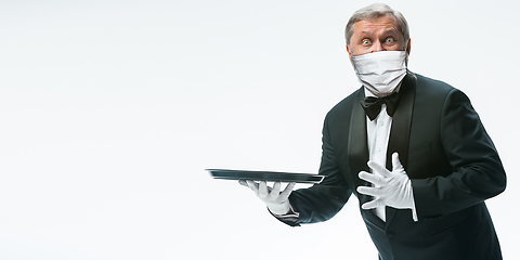 Image showing Elegance senior man waiter in protective face mask on white background. Flyer with copyspace.