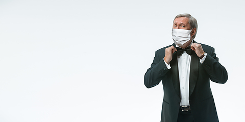 Image showing Elegance senior man waiter in protective face mask on white background. Flyer with copyspace.