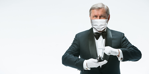 Image showing Elegance senior man waiter in protective face mask on white background. Flyer with copyspace.