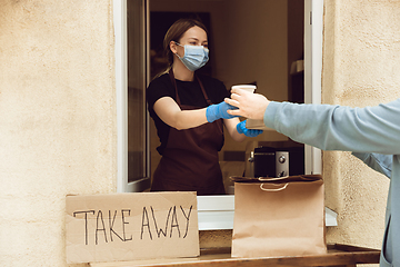 Image showing Woman preparing drinks and meals, wearing protective face mask and gloves. Contactless delivery service during quarantine coronavirus pandemic. Take away only concept.