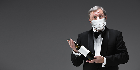 Image showing Elegance senior man waiter in protective face mask on gray background. Flyer with copyspace.