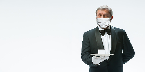 Image showing Elegance senior man waiter in protective face mask on white background. Flyer with copyspace.